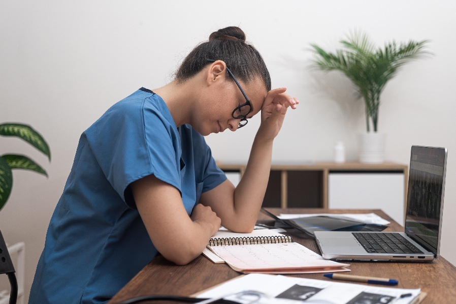 clinician overwhelmed in front of laptop