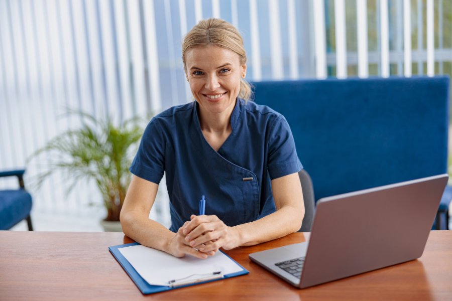 Happy clinician reviewing patient documentation on a laptop using AI-powered clinical notes technology like ScribePT to improve EMR usability and reduce documentation workload.